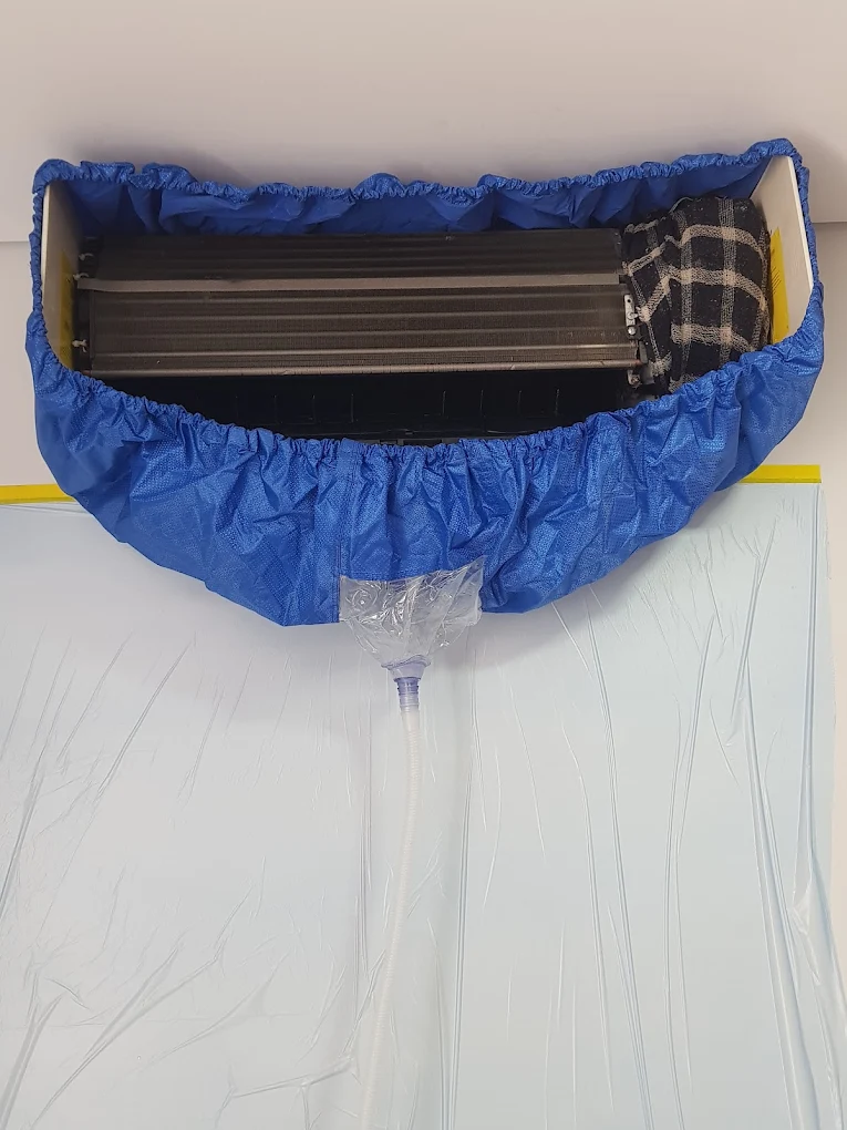 Higienização de ar-condicionado Split com bolsa coletora azul e plástico protegendo a parede