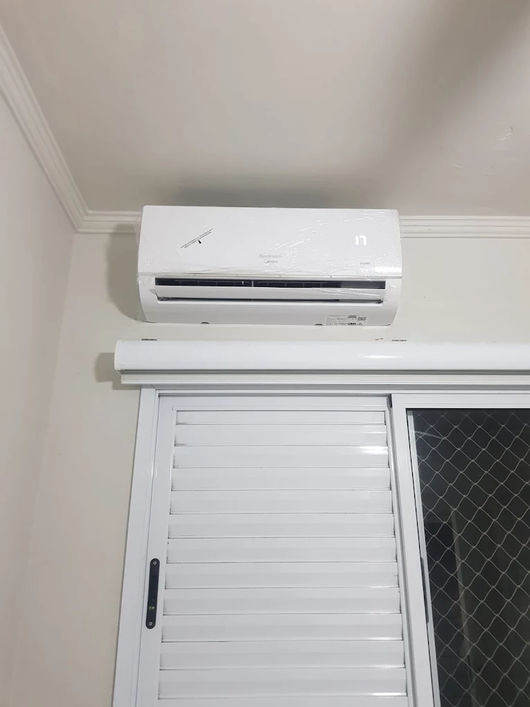 Ar-condicionado Split instalado acima da janela de um quarto, com acabamento limpo
